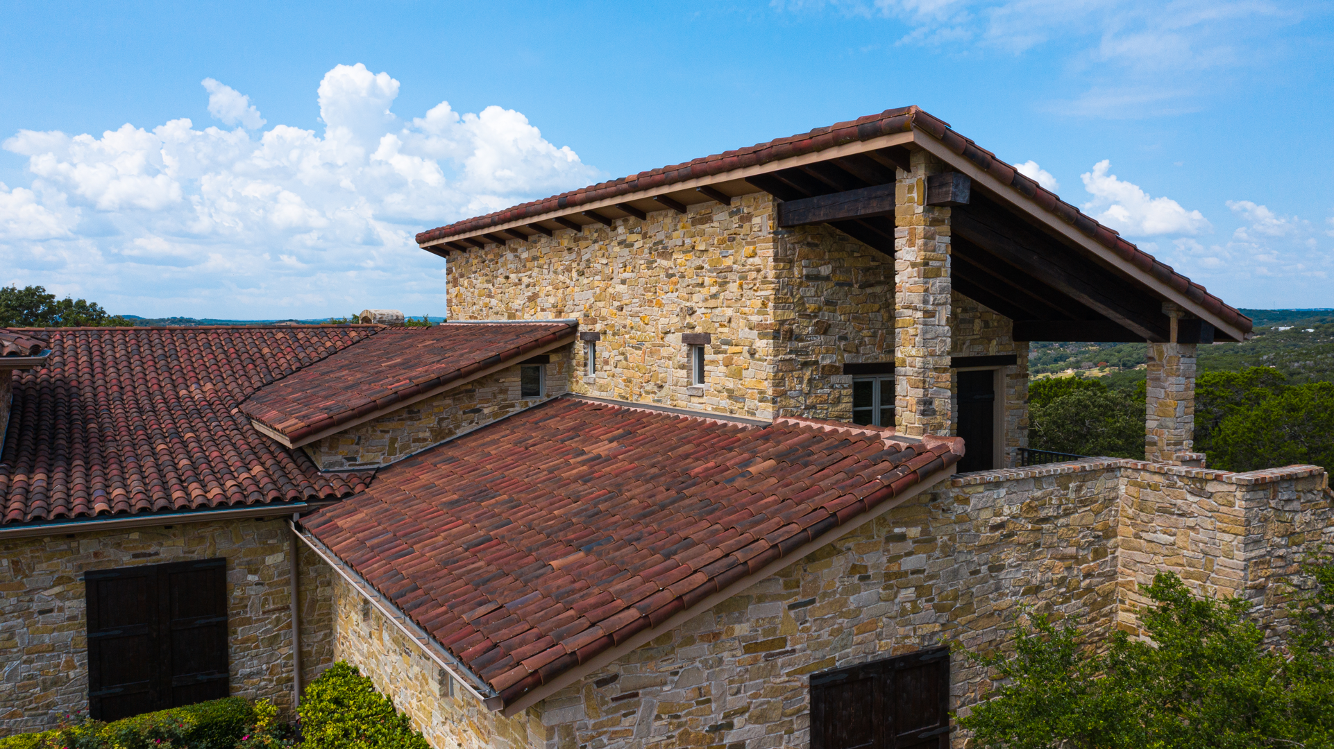 Handmade clay tile roof on a two-story residential property, installed by Schulte Roofing in Ingram, Texas.