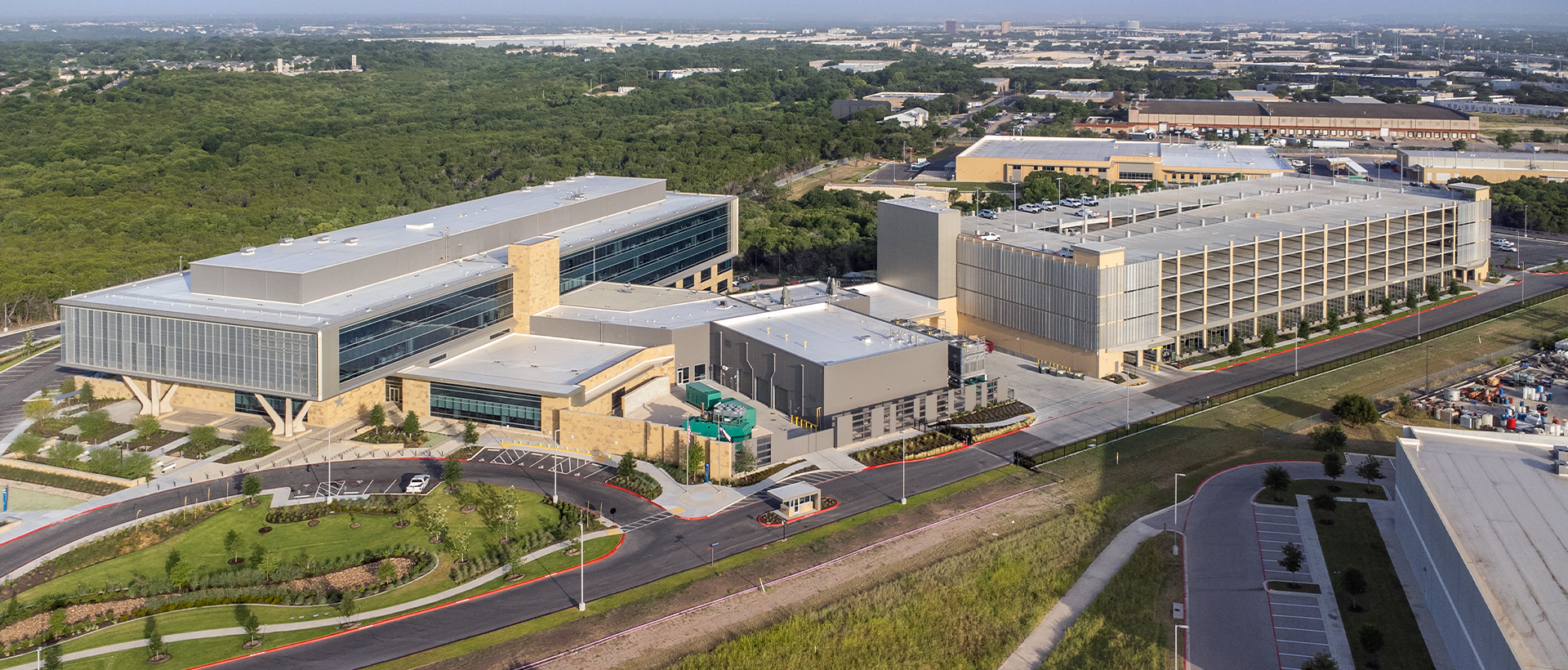 Texas Department of Public Safety's finished commercial flat roof by Schulte Roofing with view of the entire campus including parking garage, entrance, and skyline.