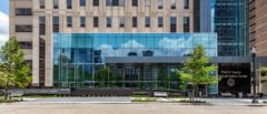 The Harris County Criminal Justice Center entryway from street view with the reflection of adjacent buildings in the window. Membrane roofing completed by Schulte Roofing.