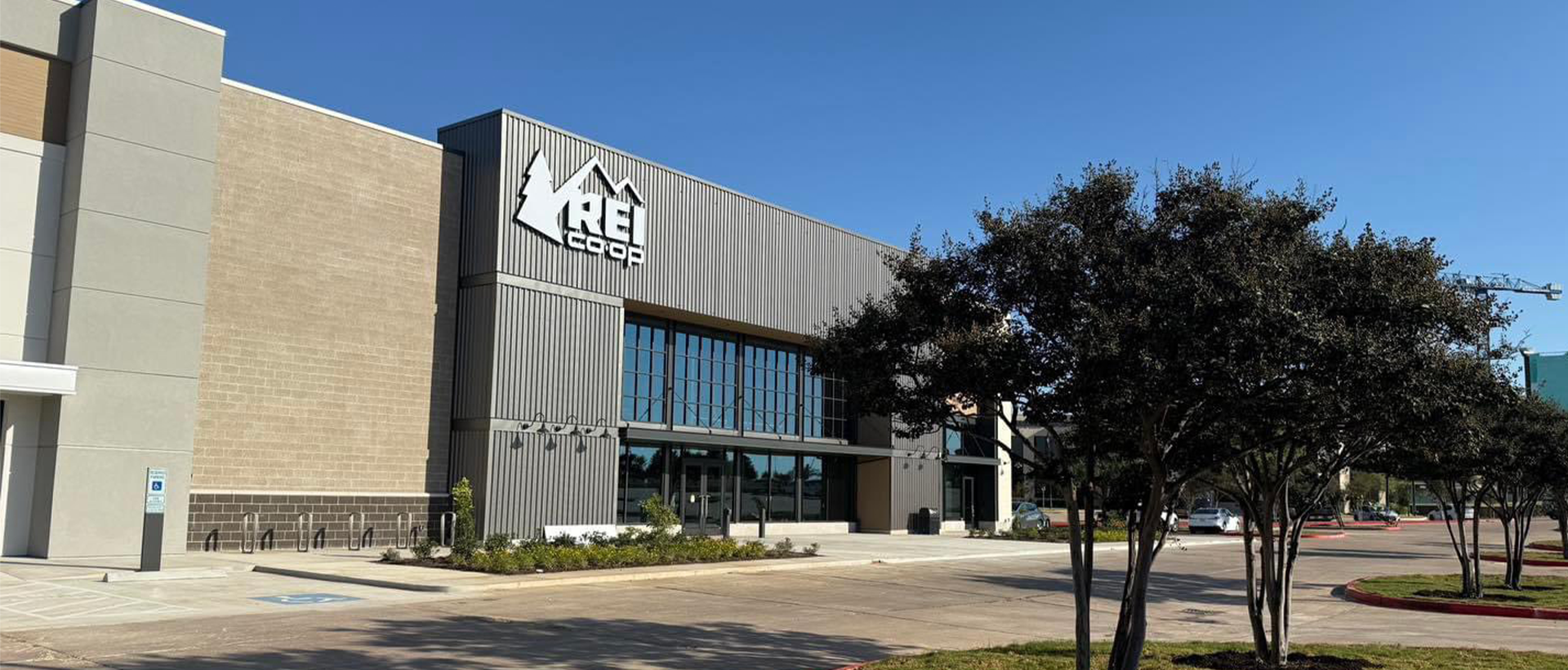 REI building facade with finished landscaping and entrance into the store. Commercial roof finished by Schulte Roofing.